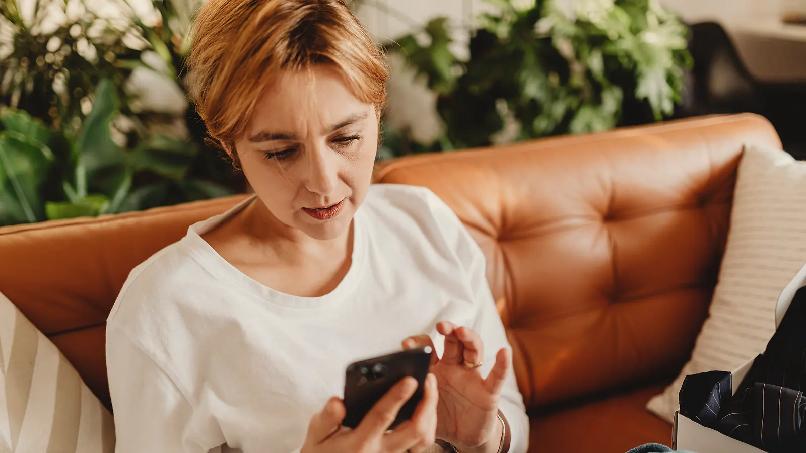 Una mujer mira el celular en el living de su casa.